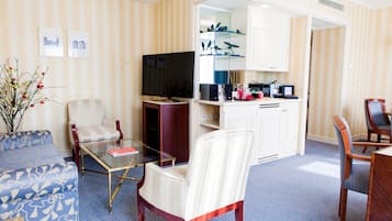 Une chambre d’hôtel comprenant un coin salon, une table à manger, un téléviseur et un coin cuisine.