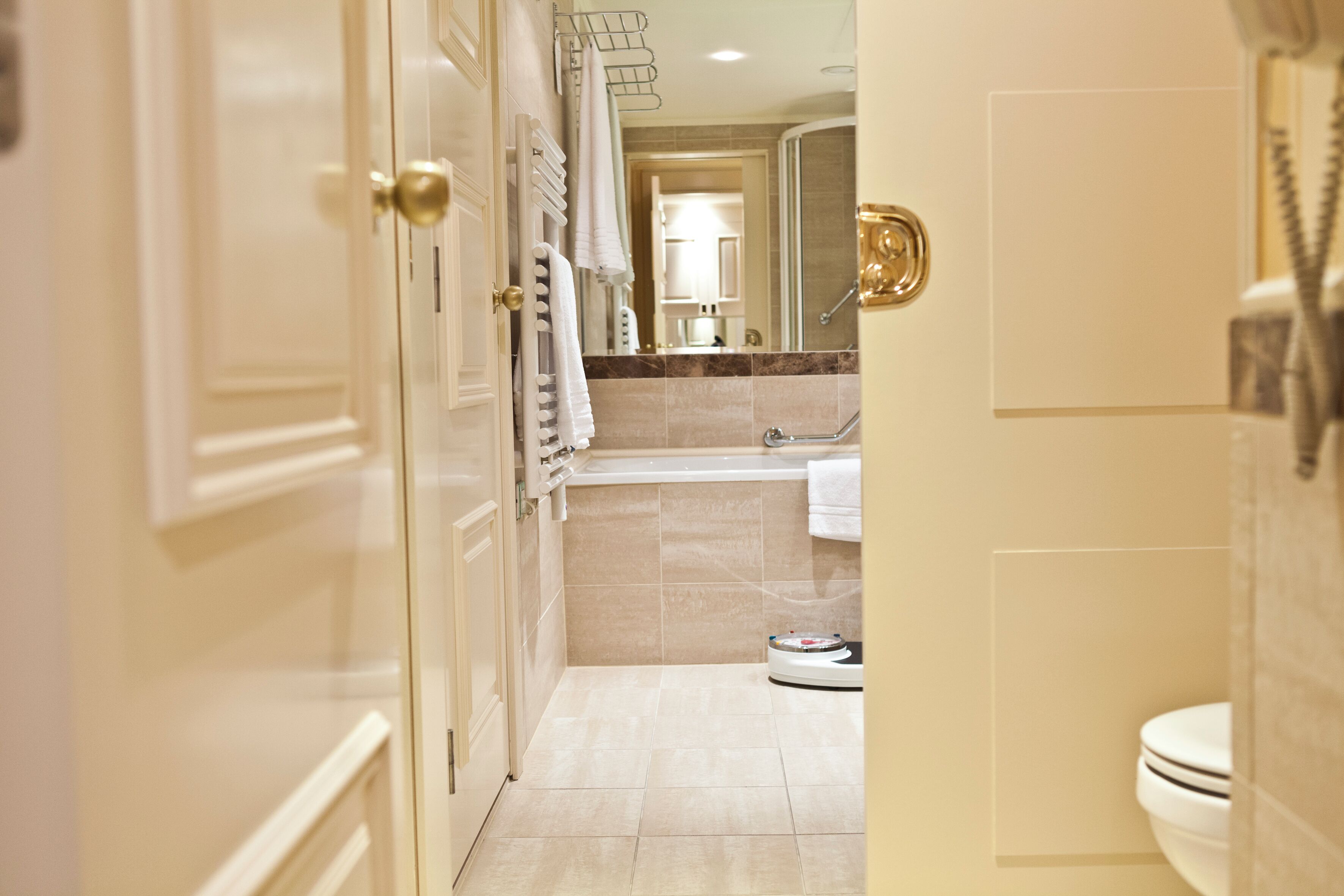 Een hotelbadkamer met een bad, toilet en een weegschaal op de vloer.