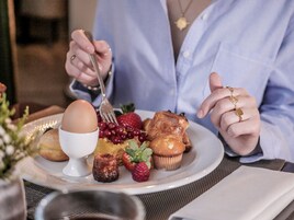 En morgenmadstallerken med æg, jordbær og muffins.