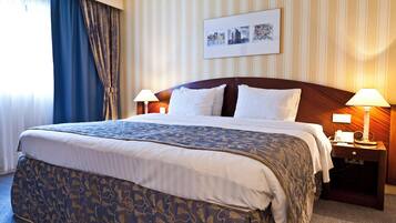 A hotel room with a large bed, two bedside lamps, a nightstand, and a framed picture on the wall.