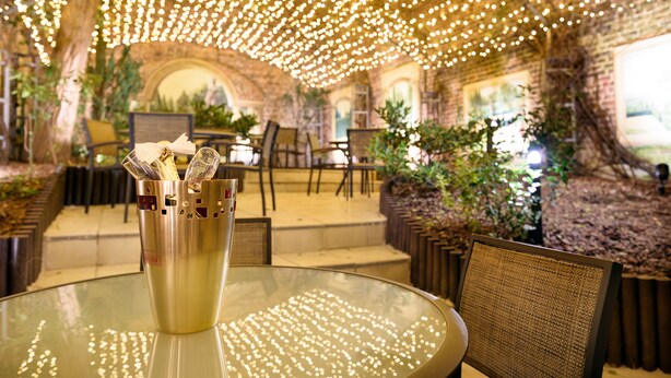 A restaurant with a glass table, chairs, and a decorative light fixture.
