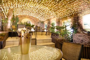 Un restaurante con mesa de vidrio, sillas y una lámpara decorativa.