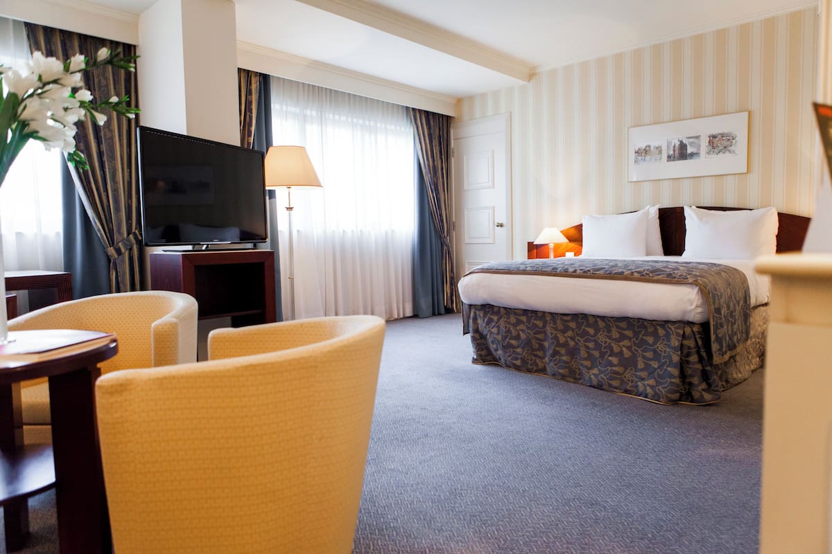 A hotel room with a bed, a TV, a desk, and a chair.