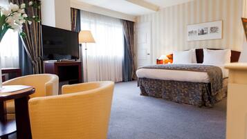 A hotel room with a bed, a TV, a desk, and a chair.