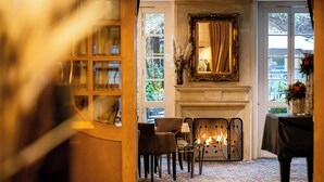 A room with a fireplace, chairs, a table, and a mirror.