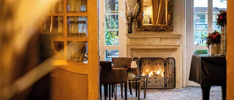 A room with a fireplace, chairs, a table, and a mirror.