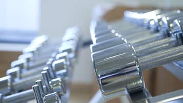 A close-up of a row of shiny, metallic dumbbells arranged in a gym setting.