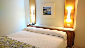 A hotel room with a bed, a bedside table with a lamp, and a framed picture on the wall.