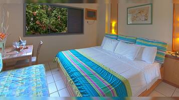 Un dormitorio con cama, mesita de noche, silla, ventana con vistas a zonas verdes y aire acondicionado instalado en la pared.