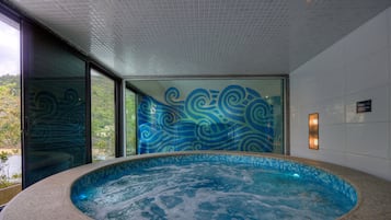 Relax by the pool surrounded by a grid-patterned ceiling and a clear glass door leading to an outdoor area.