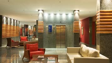Un hall con mostrador de recepción, zona de estar y ascensor.