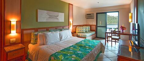 Habitación de hotel con cama, escritorio, silla, mesita de noche y ventana con vistas.