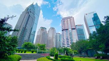 A cityscape with modern skyscrapers, a park with well-maintained greenery, and a clear sky.