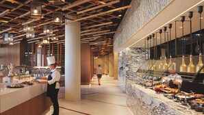 Un moderno vestíbulo de hotel con un mostrador de recepción de mármol, vigas de madera en el techo y una pared de mármol con un diseño geométrico.