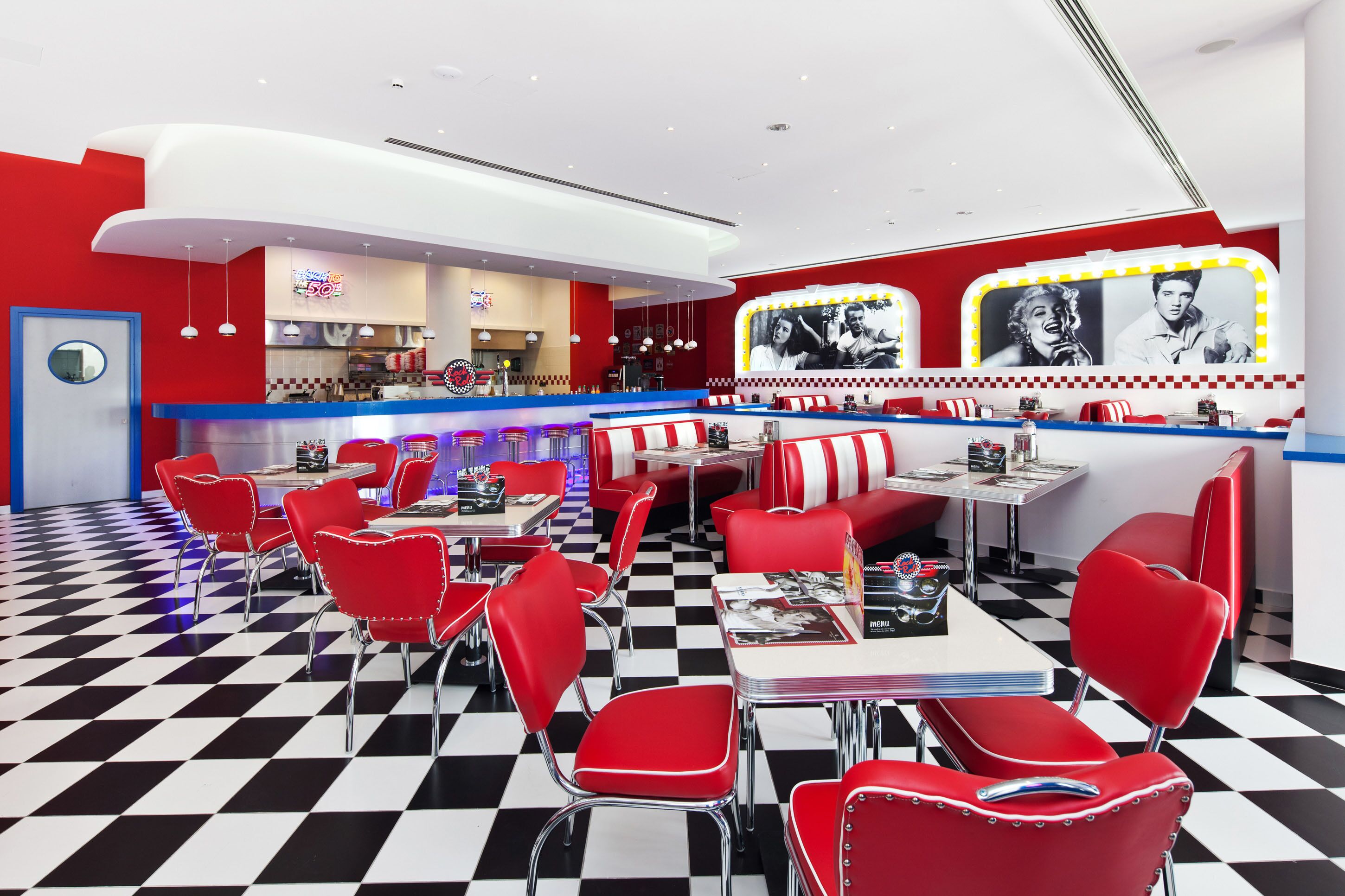 A retro diner interior with checkered flooring, red and white booths, and a counter area.