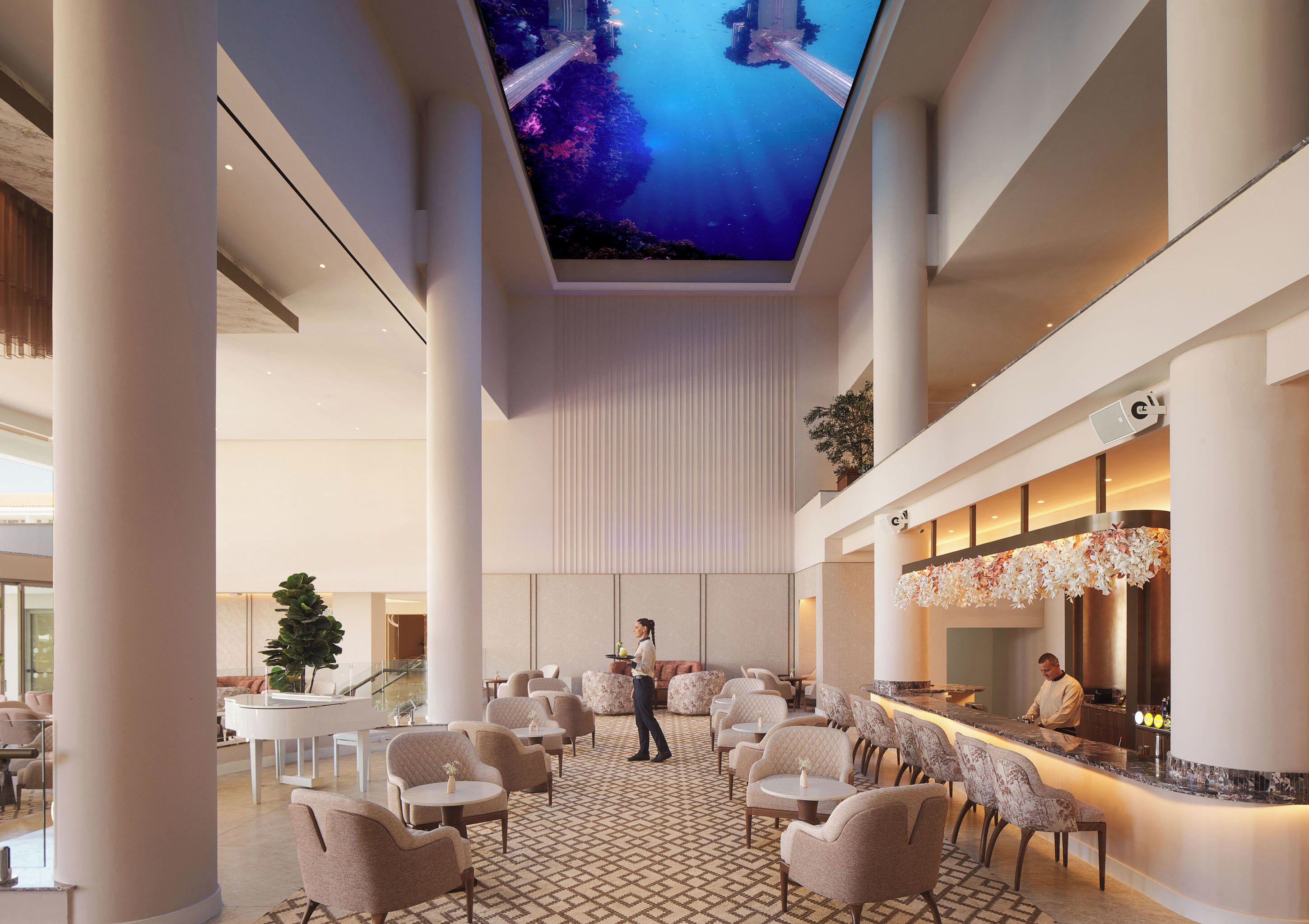Un hall d’entrée spacieux doté d’un grand écran au plafond, de plusieurs espaces de détente et d’un bar.