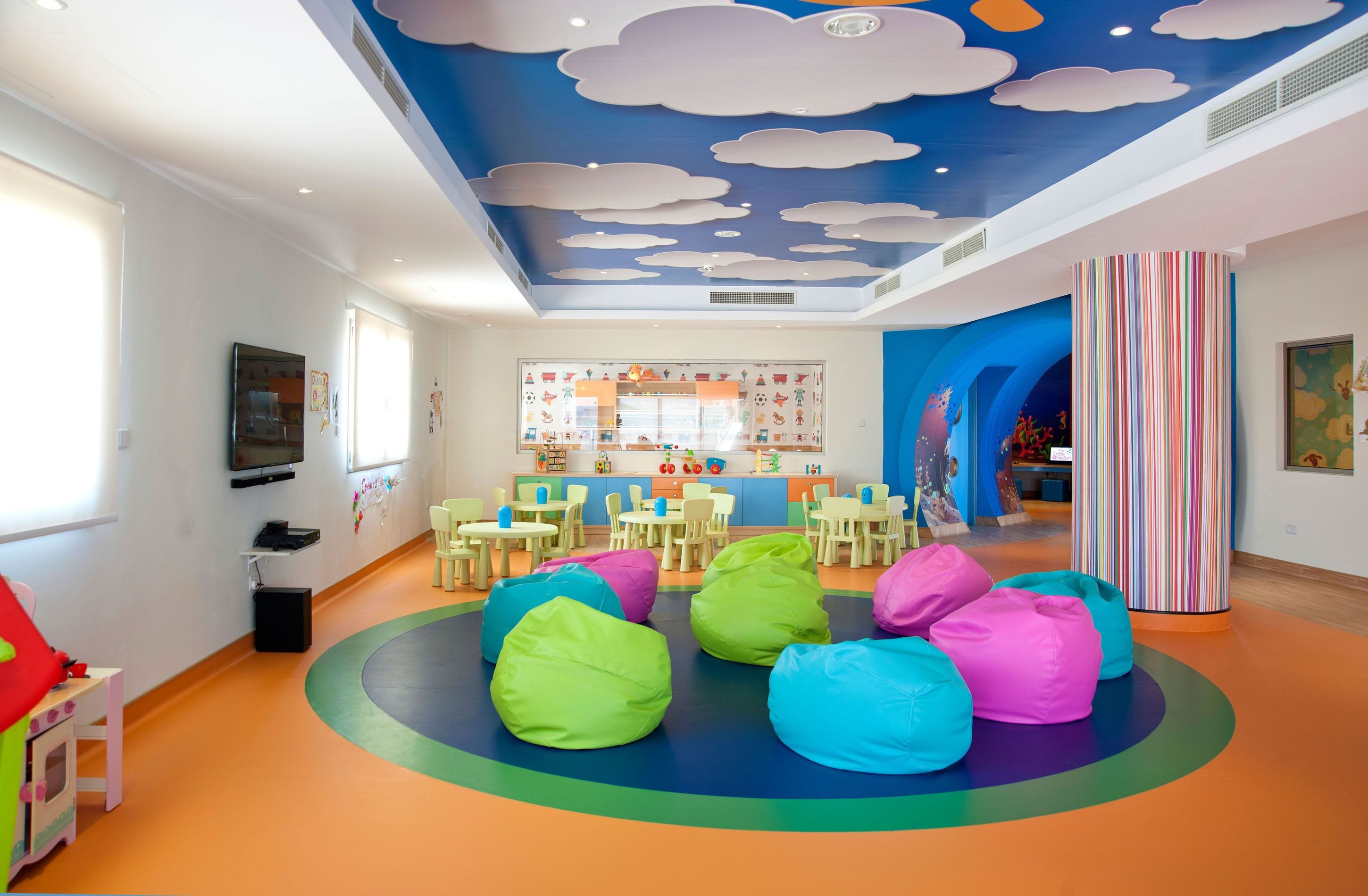 A children's playroom with colorful bean bags, a play area, and educational posters on the walls.