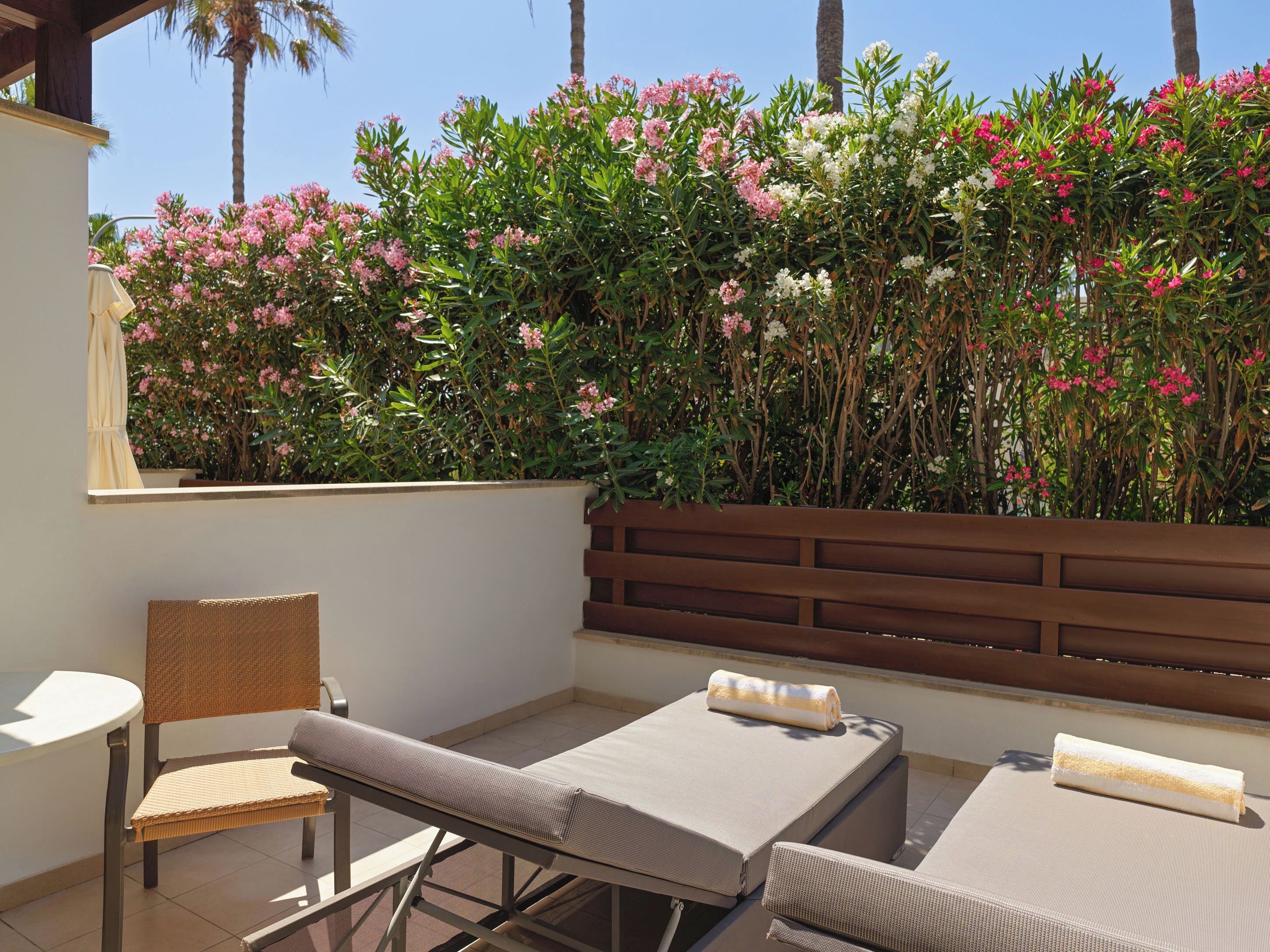 A patio with two lounge chairs, a wicker chair, and a white table.