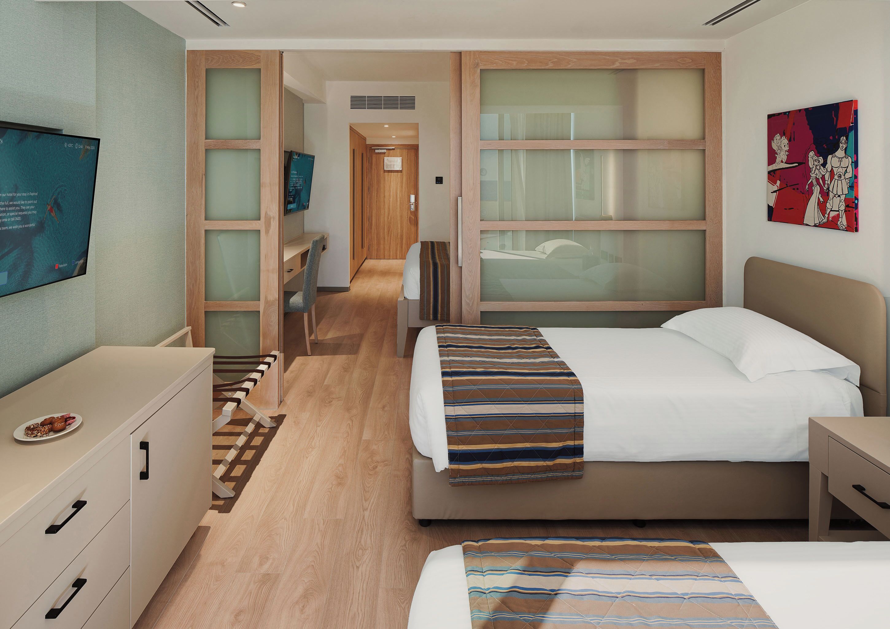 A hotel room with a bed, a desk, a TV, and a wardrobe.