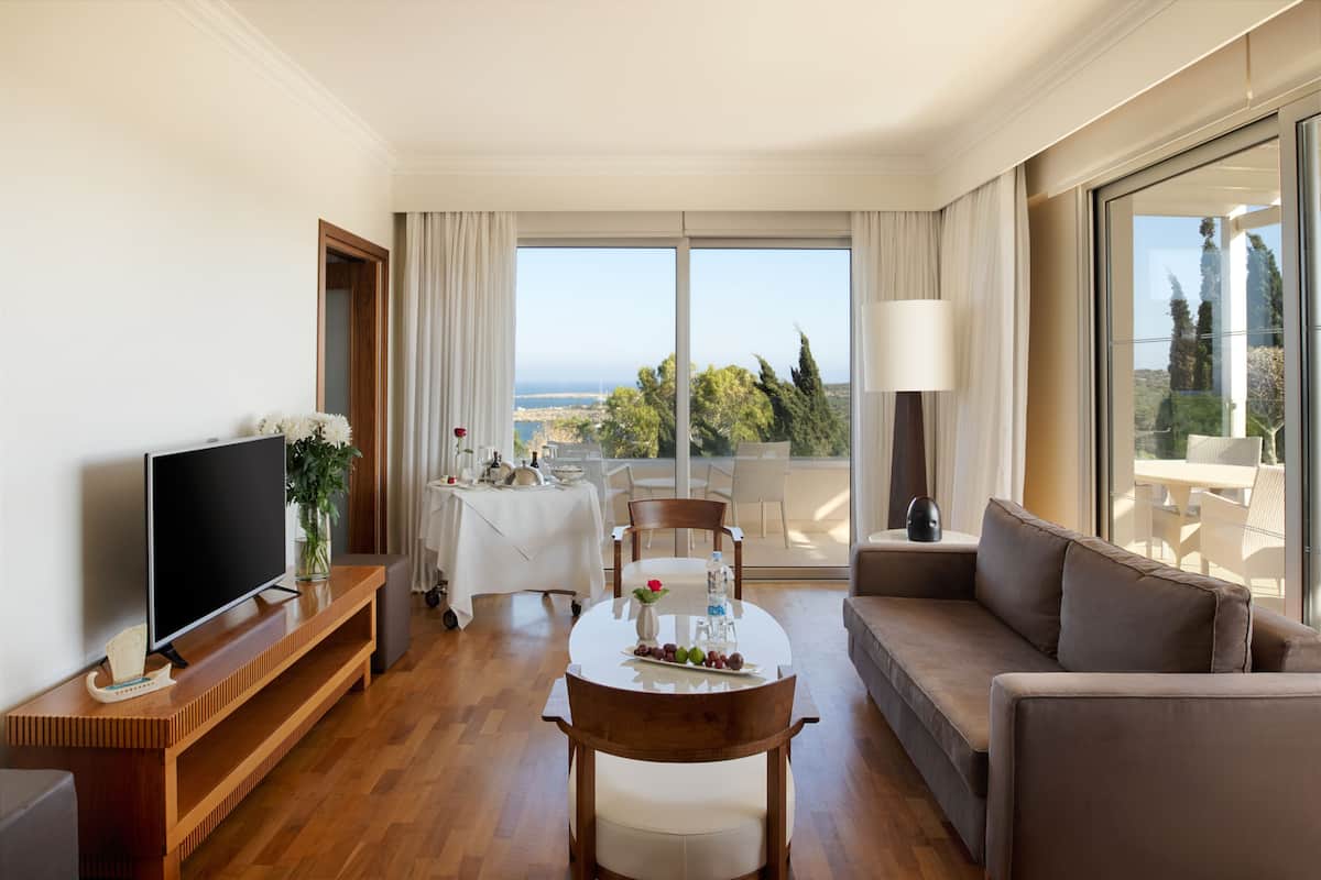 Une chambre d’hôtel moderne dotée d’un balcon, d’un coin repas, d’un canapé et d’une télévision.