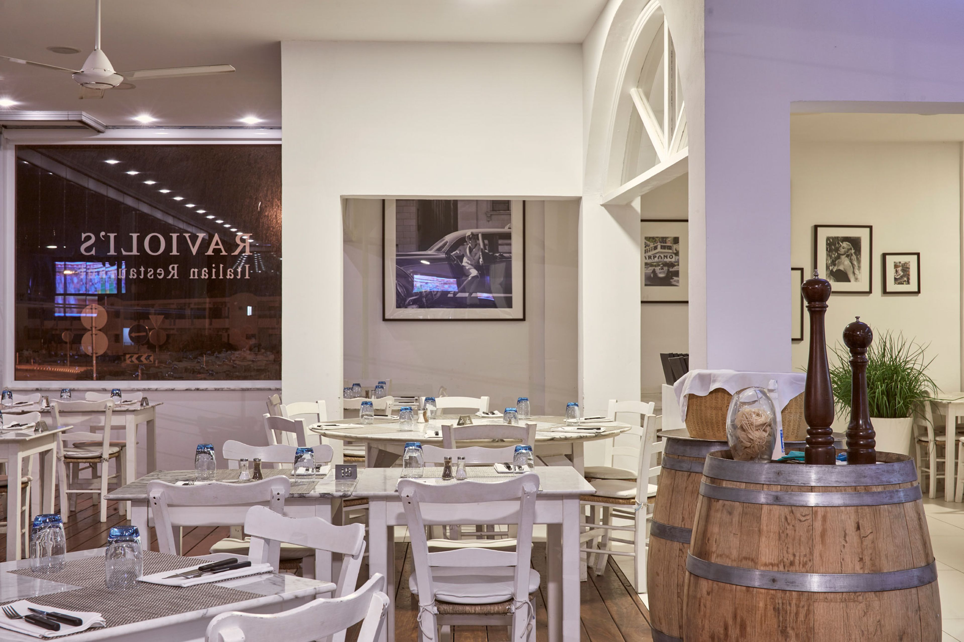 A restaurant with white furniture, a television screen, and framed pictures on the wall.