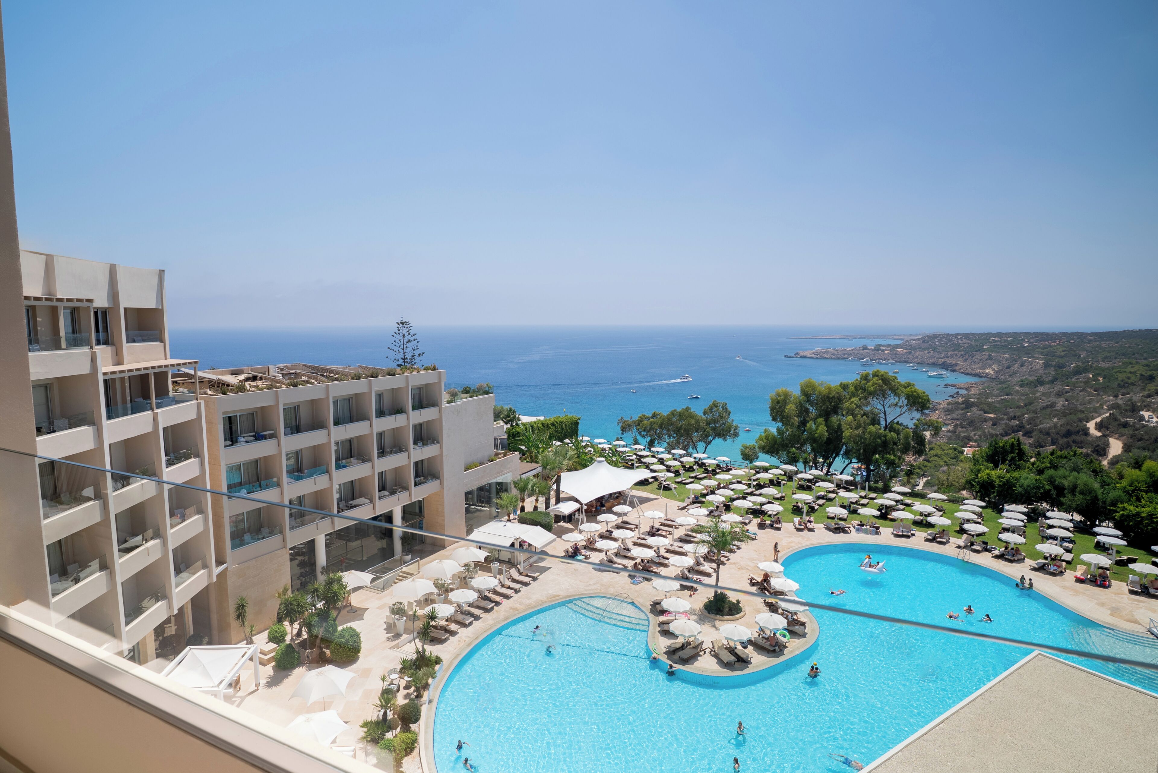Ein Hotel mit großem Pool, mehreren Balkonen und Meerblick.