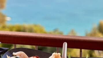 A plate of sushi with various types of fish and toppings, placed on a table with a view of the ocean in the background.