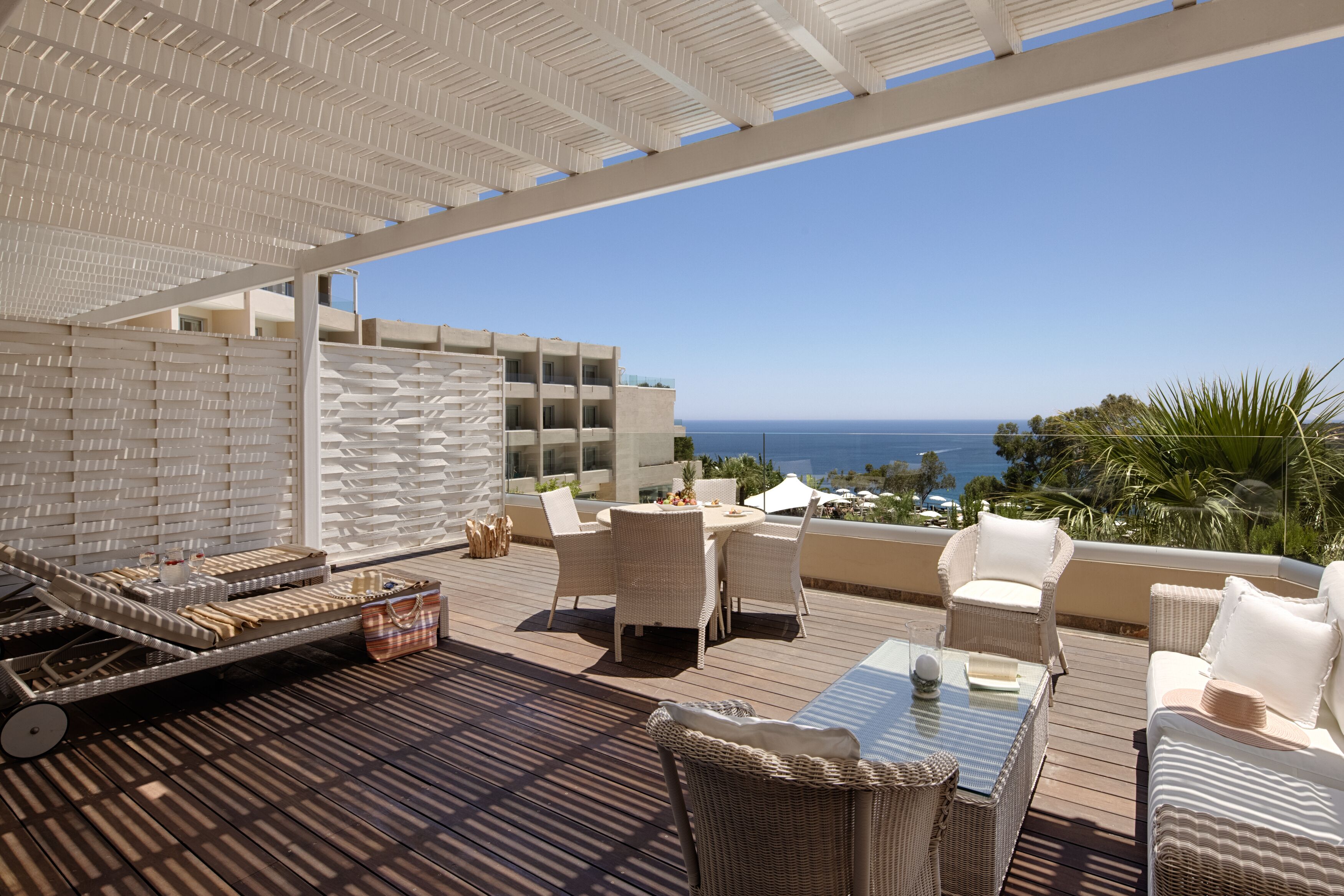 A terrace with wicker furniture, a table, and a sun lounger.