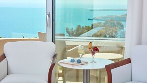 A balcony with a view of the sea, a table with a glass of wine, a book, and sunglasses. - Grecian Park Hotel (Paralimni)