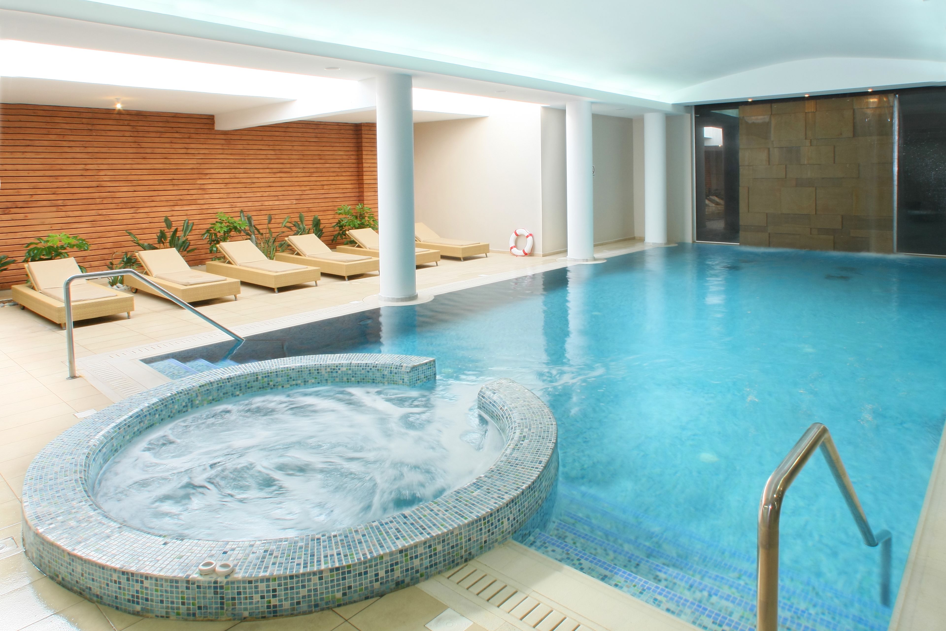 Piscina con sillas de descanso y zona de hidromasaje.