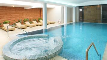 A swimming pool with lounge chairs and a hot tub area.