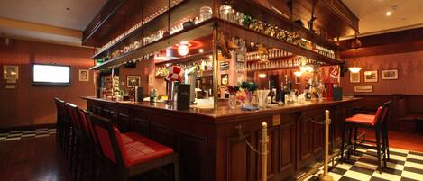 A bar area with wooden bar counters, red cushioned bar stools, and a checkered floor.