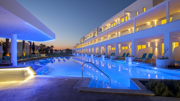 A modern hotel with a pool area, multiple balconies, and lounge chairs. - Aliathon Aegean (Geroskipou)