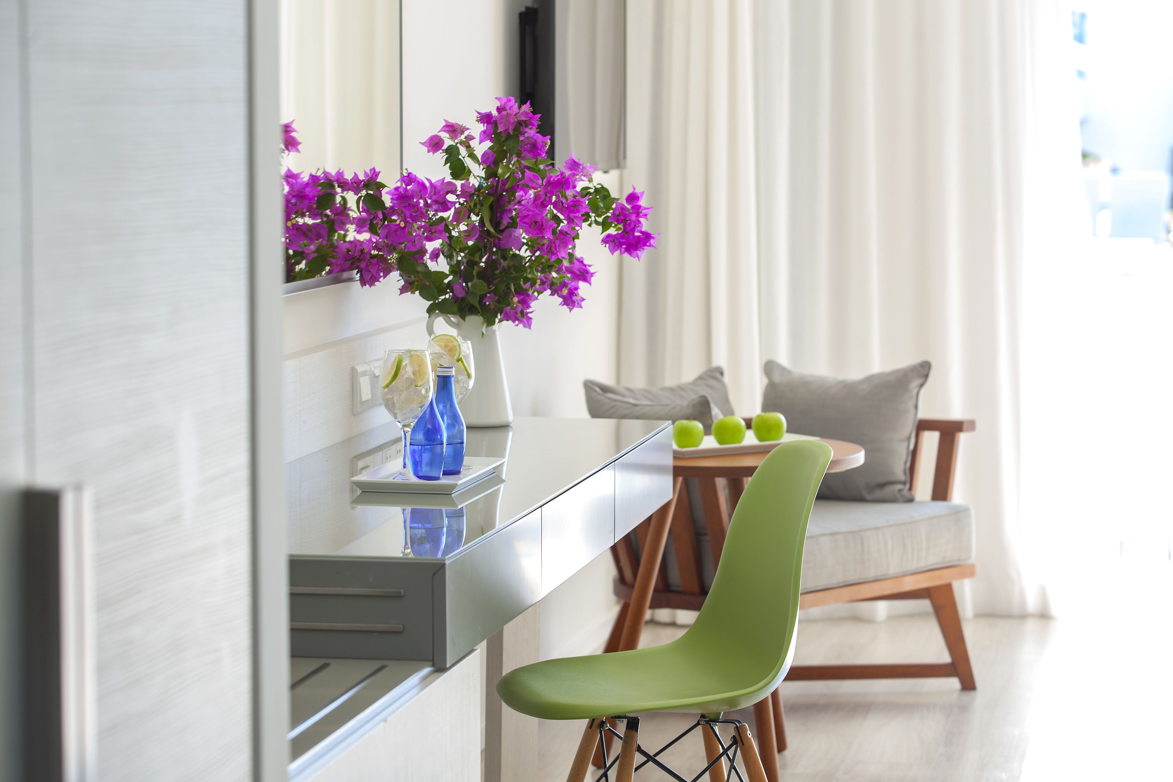 Eine moderne Küche mit weißer Arbeitsplatte, einem grünen Stuhl und einer Vase mit lila Blumen.
