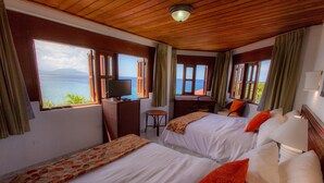 Habitación de hotel con dos camas, un escritorio, una silla y un televisor.