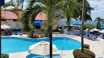 Alberca al aire libre, sombrillas en la alberca y camastros