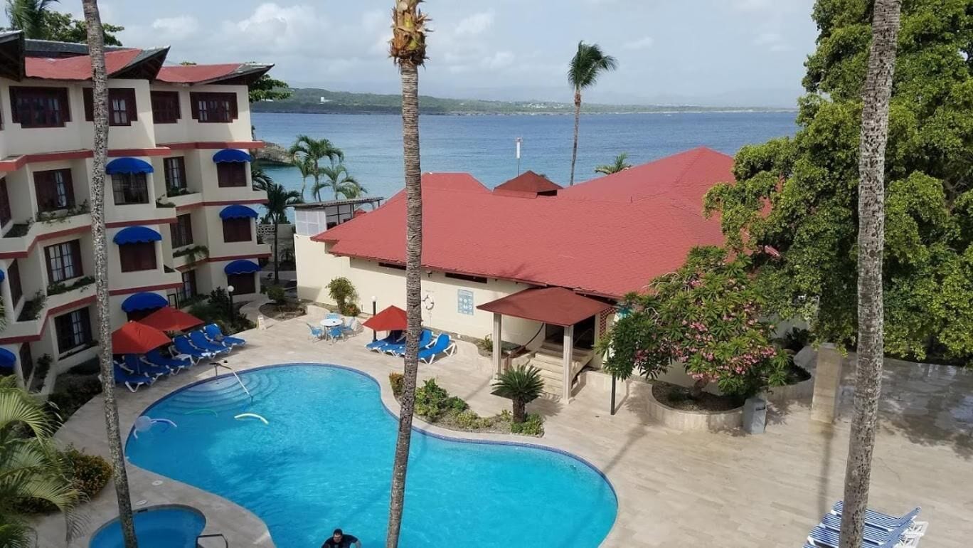 A hotel with a swimming pool, multiple balconies, and a view of the sea.