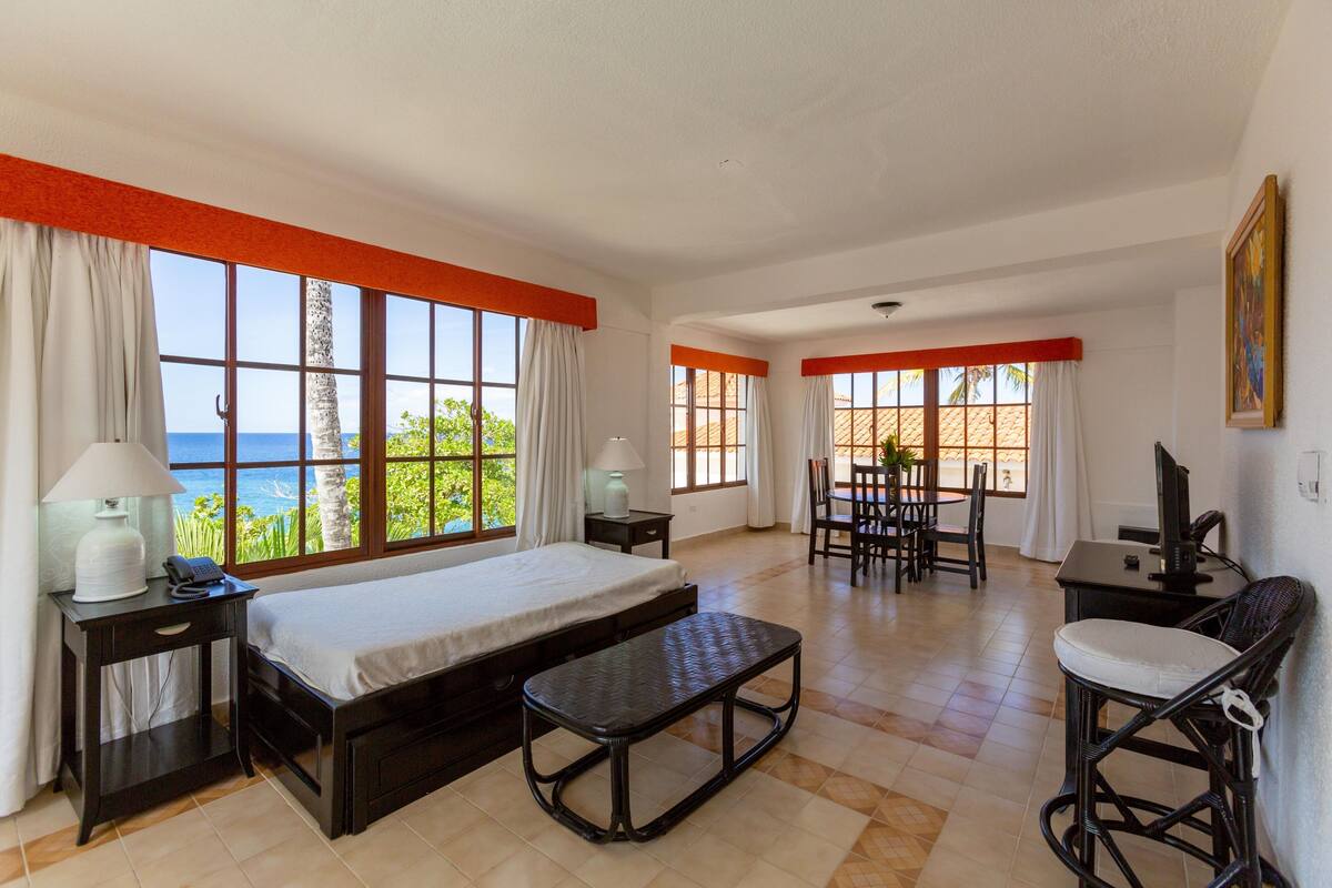 Ein Hotelzimmer mit Bett, Schreibtisch, Stuhl und Meerblick.