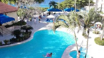 Una piscina al aire libre, sombrillas, sillones reclinables de piscina