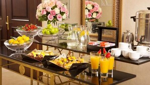 Un bufé de desayuno con diversas frutas, bollería y zumo de naranja.