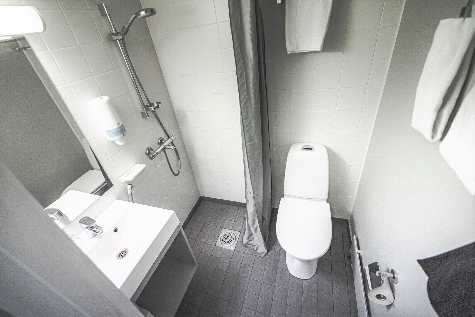 A small, compact bathroom with a toilet, sink, and shower.