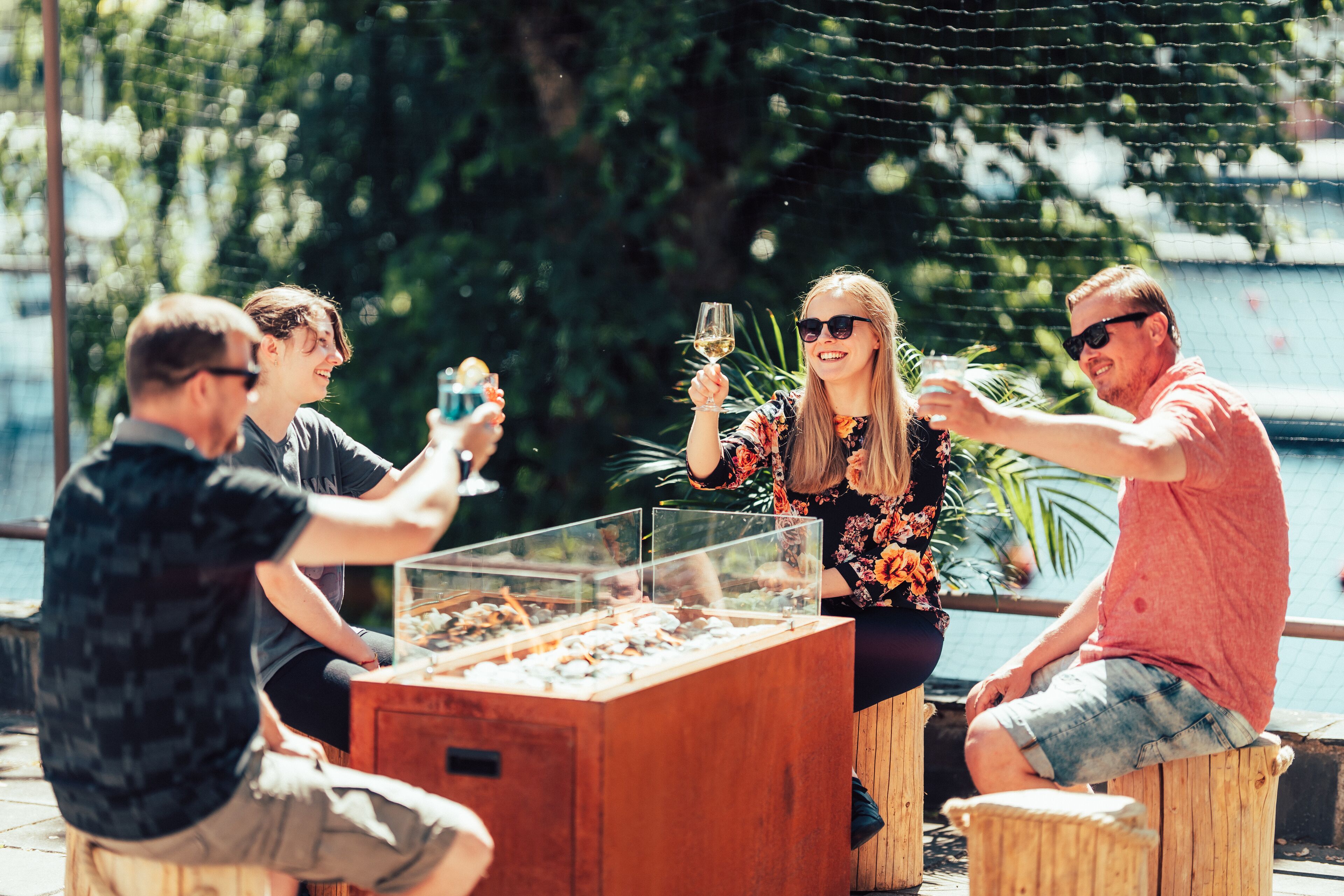 A group of people sitting at an outdoor table with a glass display case in front of them.