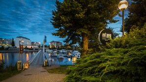 A waterfront promenade with a pedestrian bridge, marina, and a sign indicating 'est 1900'. - Spahotel Casino (Savonlinna)
