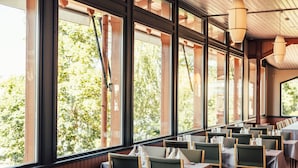 A restaurant with large windows, wooden chairs, and tables. - Spahotel Casino (Savonlinna)