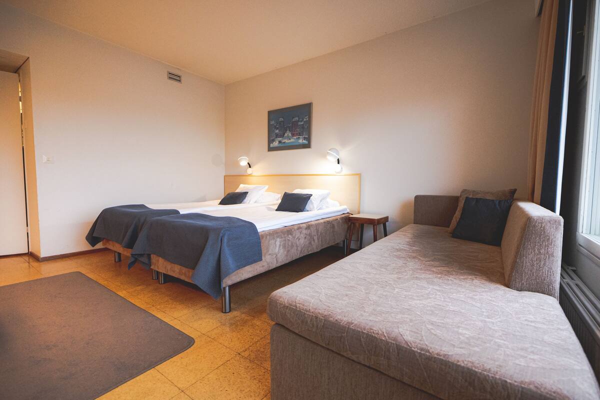 A hotel room with a bed, a sofa, and a small table.