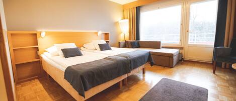 Habitación de hotel con una cama grande, un escritorio y una ventana con cortinas.