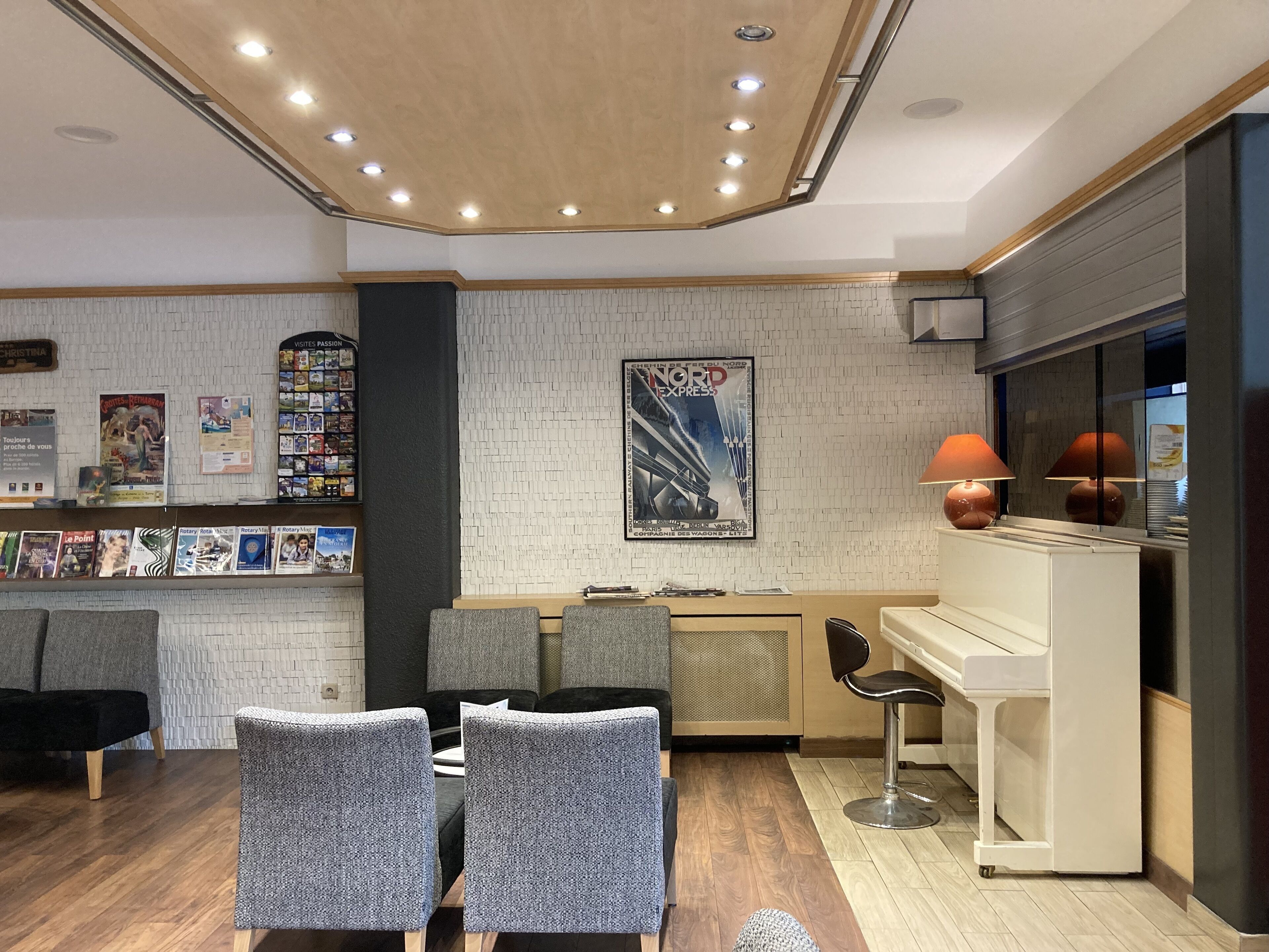 A modern interior with a reception desk, seating area, and a piano.