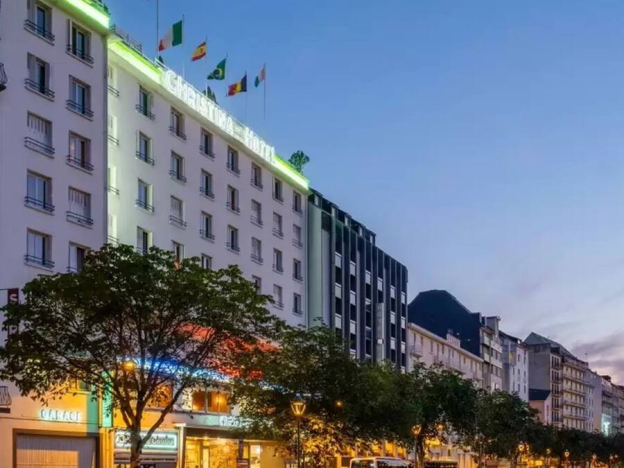 Um hotel com vários andares, bandeiras e uma placa bem visível.