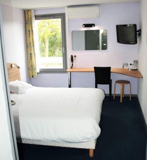 A hotel room with a bed, a desk, a chair, a television, and a window with curtains. - Comfort Hotel Valence (Valence)