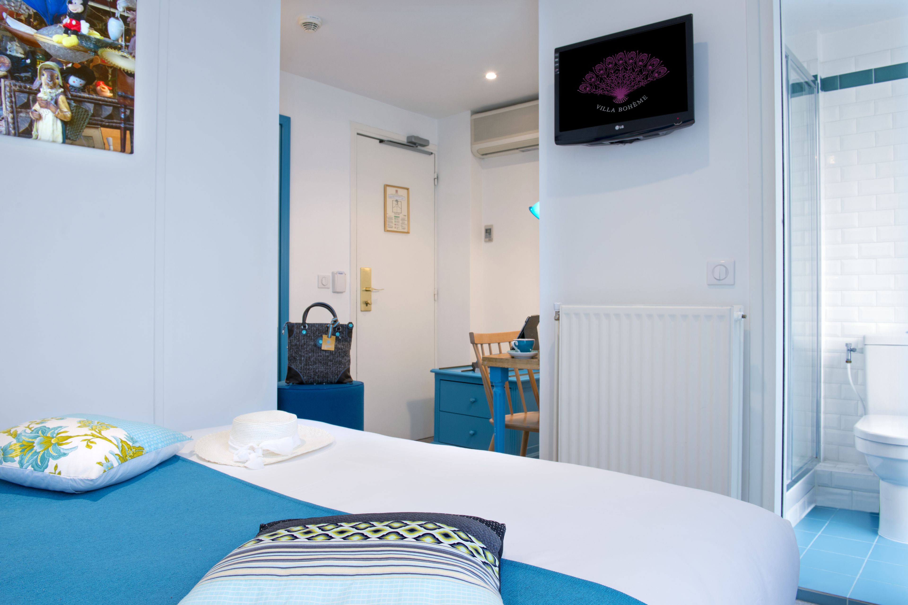 Un dormitorio con cama, televisor, escritorio y baño.